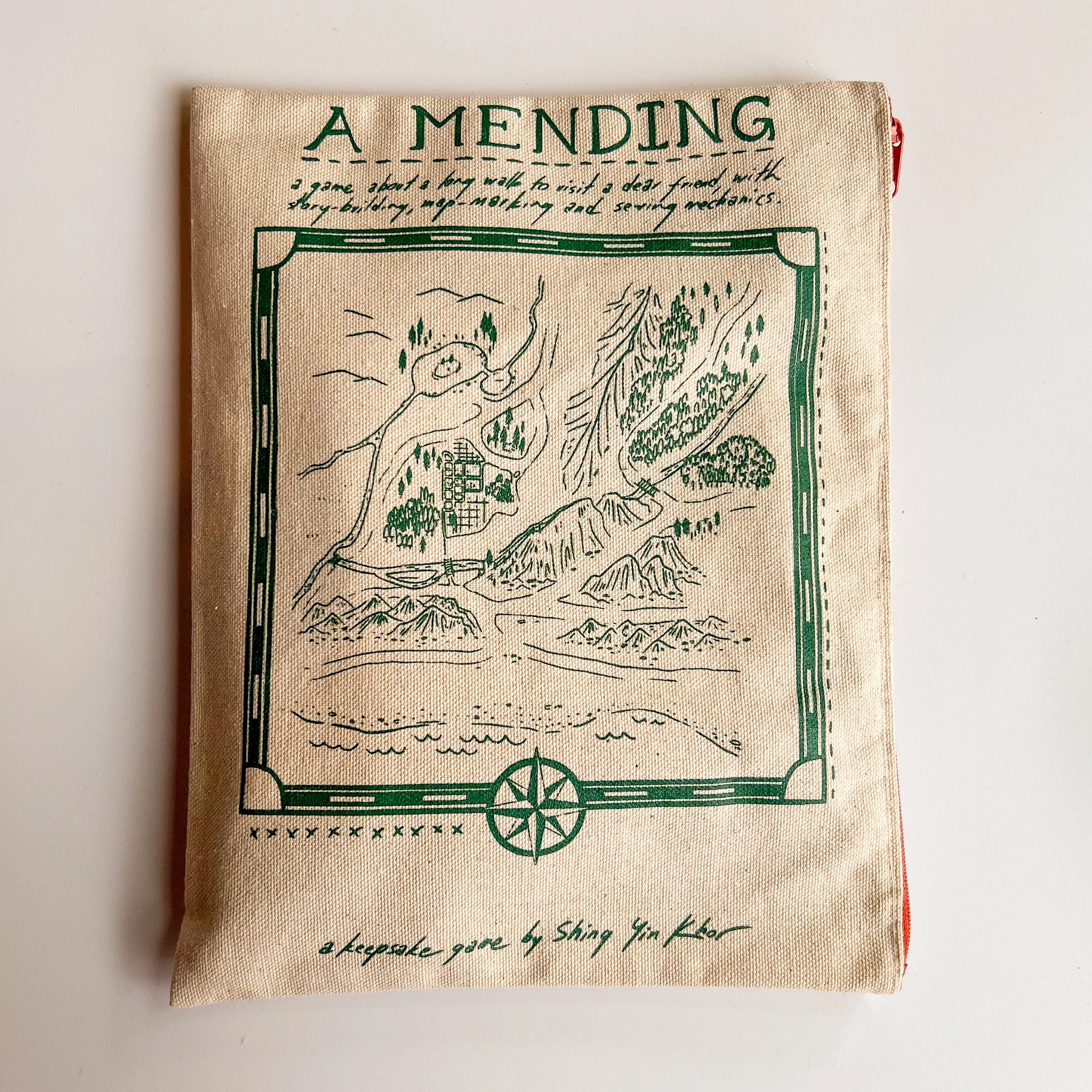 Beige cloth bag for A Mending, a solo keepsake game by Shing Yin Khor, featuring a green illustrated map.