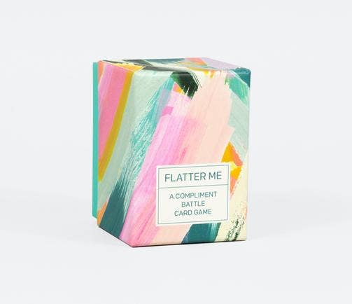 Flatter Me: A Compliment Battle Card Game in a colorful box.