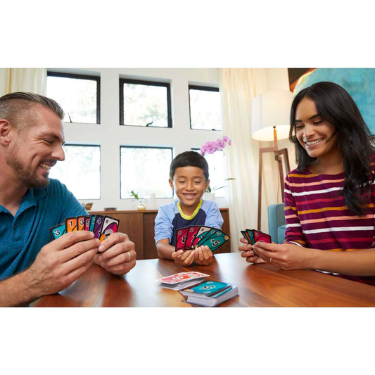 Three people play UNO Flip with a double-sided deck in a living room.