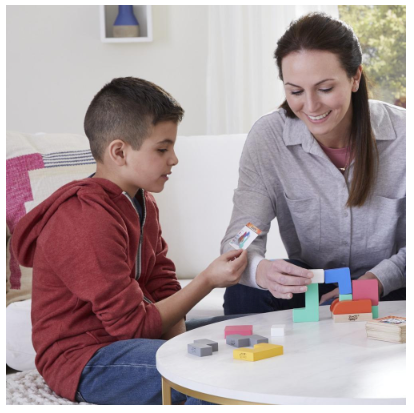 Woman and boy play Jenga Maker, a colorful building block game, together at a table.
