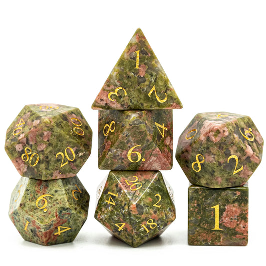 Unakite Gemstone RPG dice set by Foam Brain Games, green and pink speckled with gold numbers, shown stacked.