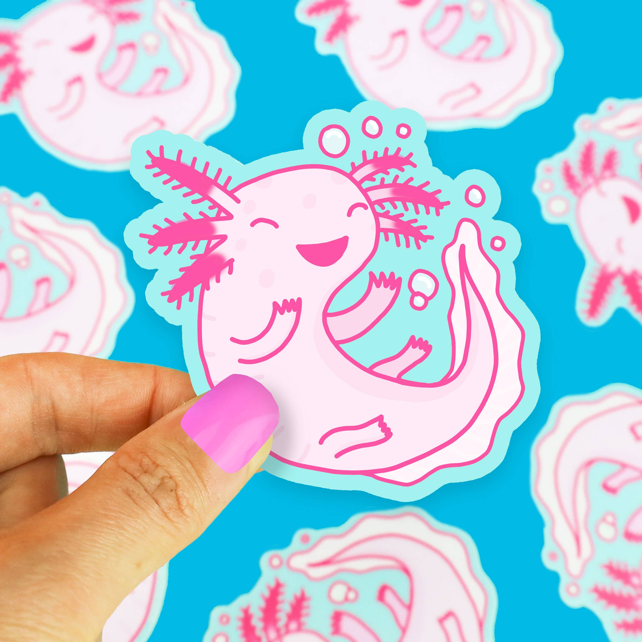 Axolotl Pink Amphibian Cute Animal Vinyl Sticker held by a hand with pink nails.