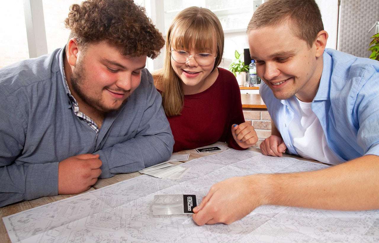 Micromacro Crime City board game being played, showing cards and a large map with three people interacting.