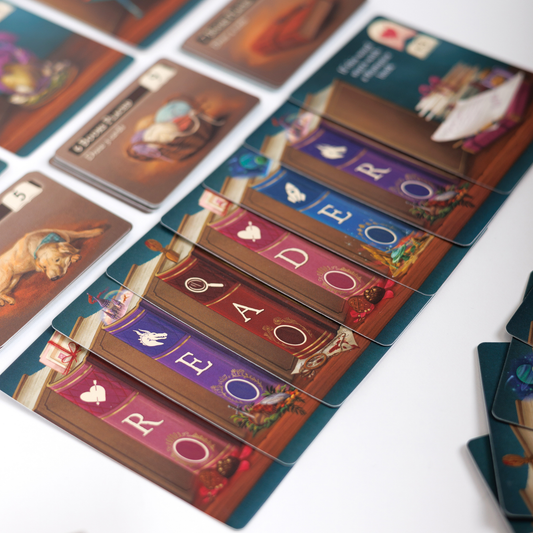 My Book Nook: A Cozy Word Building Game with illustrated cards showing books, letters, and objects on a table.