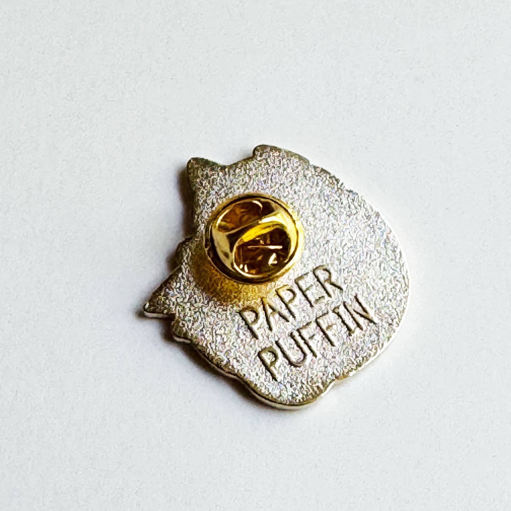 Back of Book Reader Cat enamel pin with a gold-tone butterfly clutch and embossed PAPER PUFFIN logo.