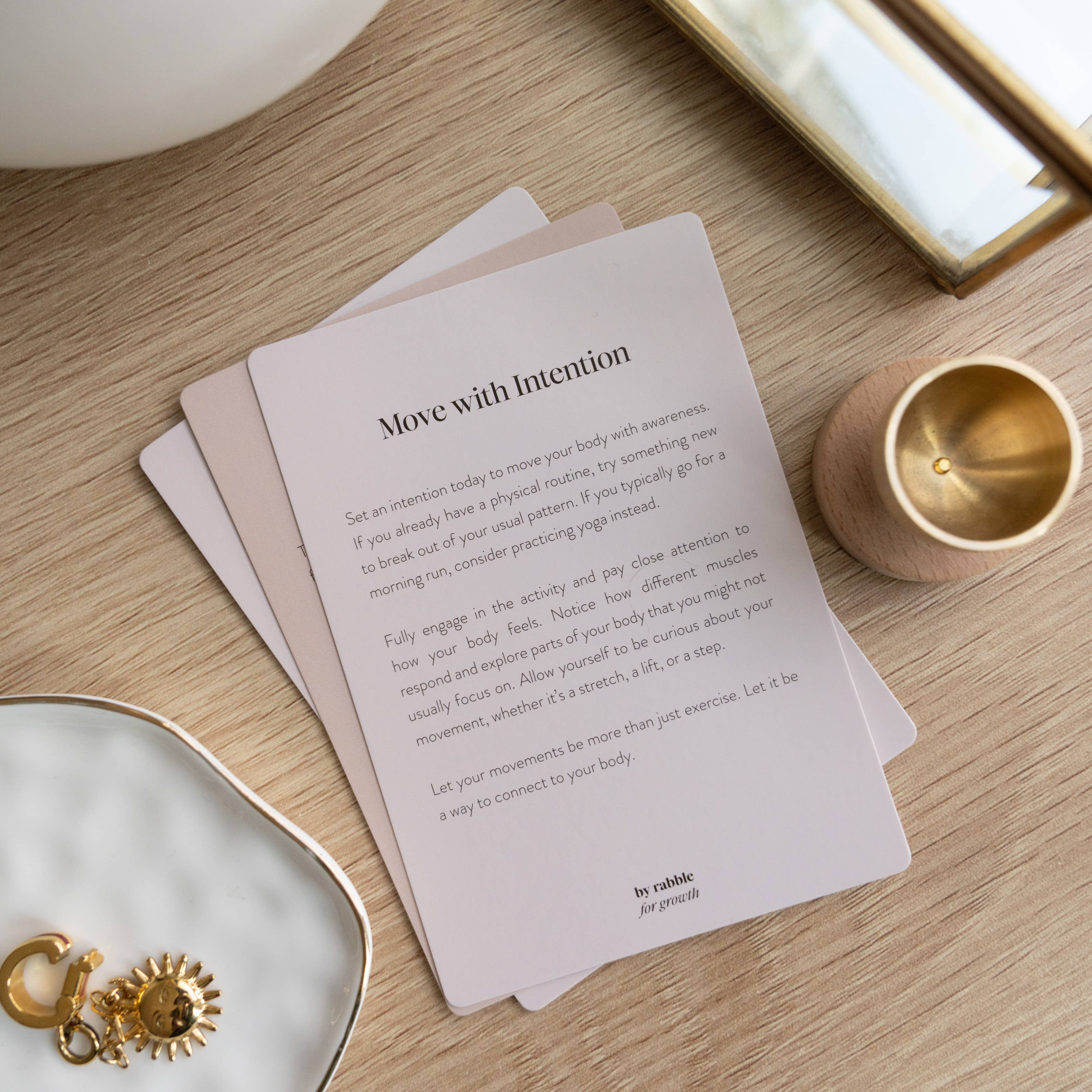 Self-Care & Affirmations card Move with Intention displayed on wood next to a gold item.