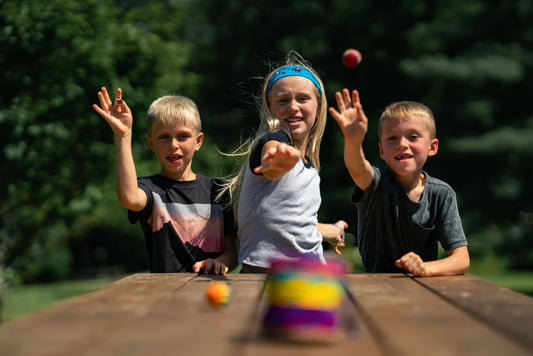 Three children play with a bright Canastaball (YippiYappa) ball stack set.