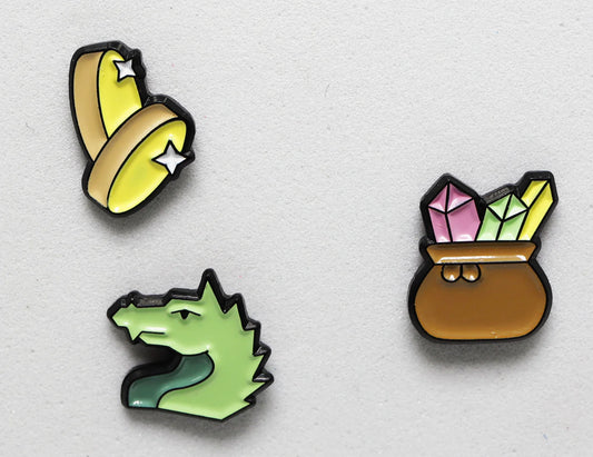 Dragons Hoard Mini Pins Pack: three metal pins featuring bananas with stars, a green dragon, and a crystal pot.