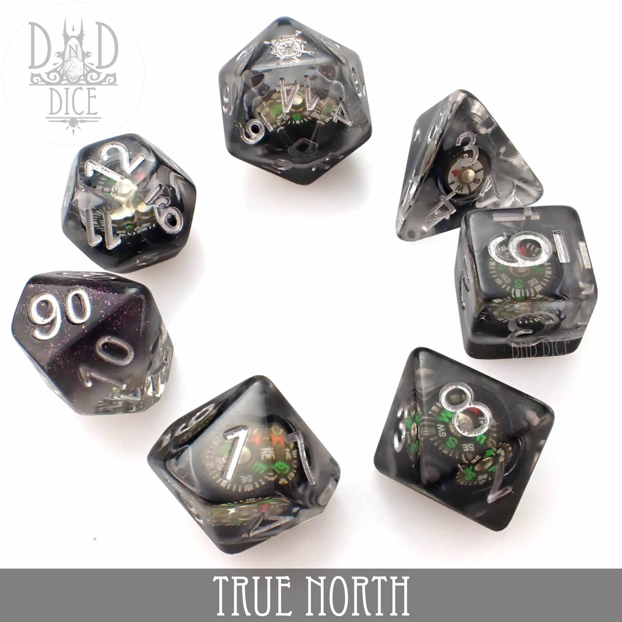 True North 7-piece black and clear resin dice set with working compasses in each die, arranged in a circle.