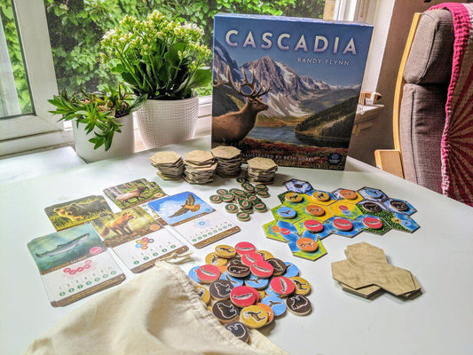 Cascadia game tiles, cards, and tokens arranged on a surface.