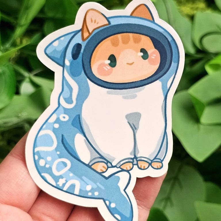 Sticker of a cartoon cat in a blue shark costume from the Cats in Sea Creature Costumes collection.
