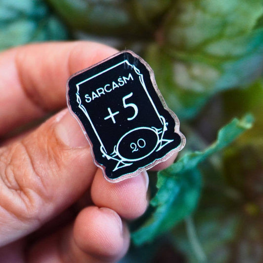 Sarcasm +5 Stat Acrylic Pin held in a hand.