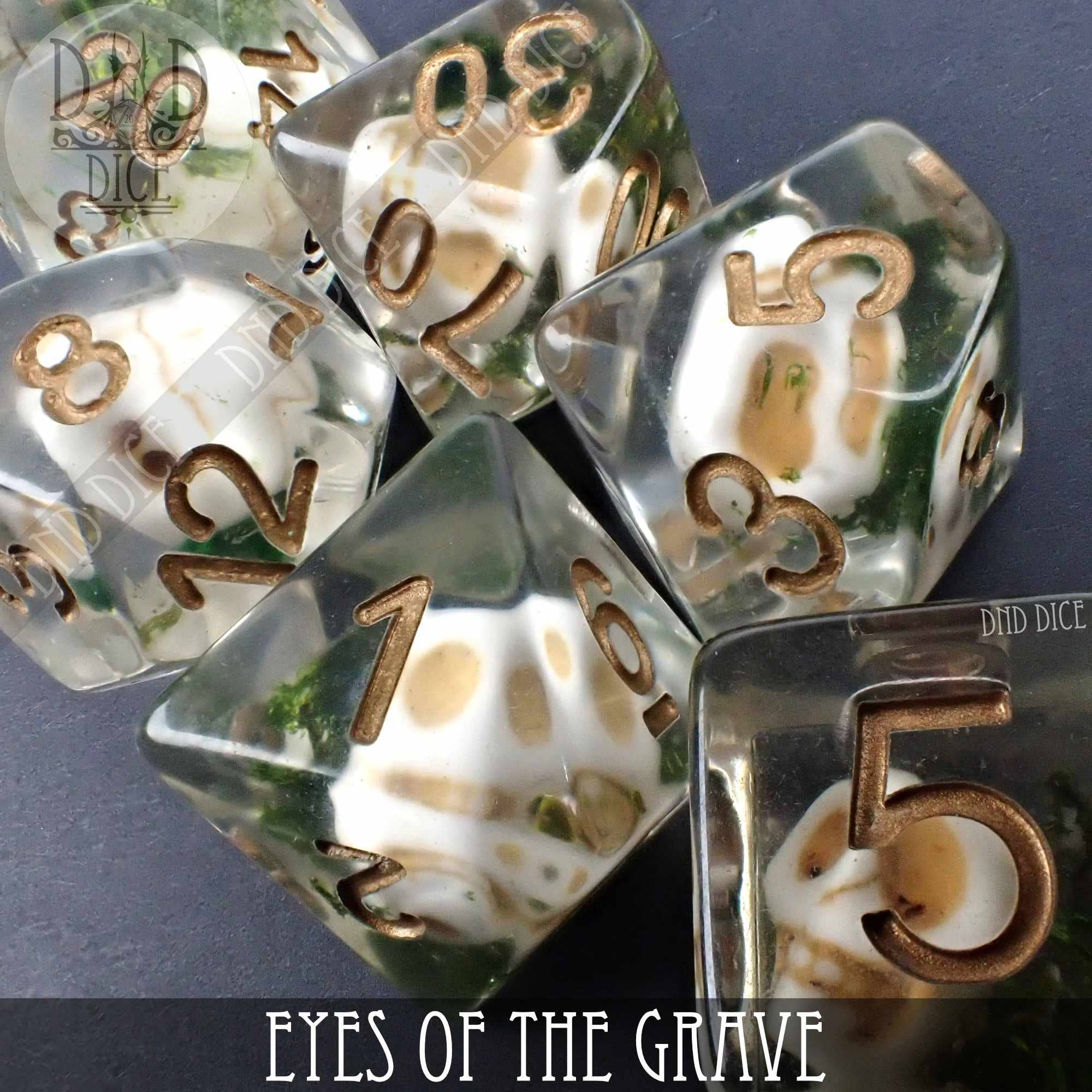 7-piece clear resin dice set with embedded tiny skulls and green moss, Eyes of the Grave variant.