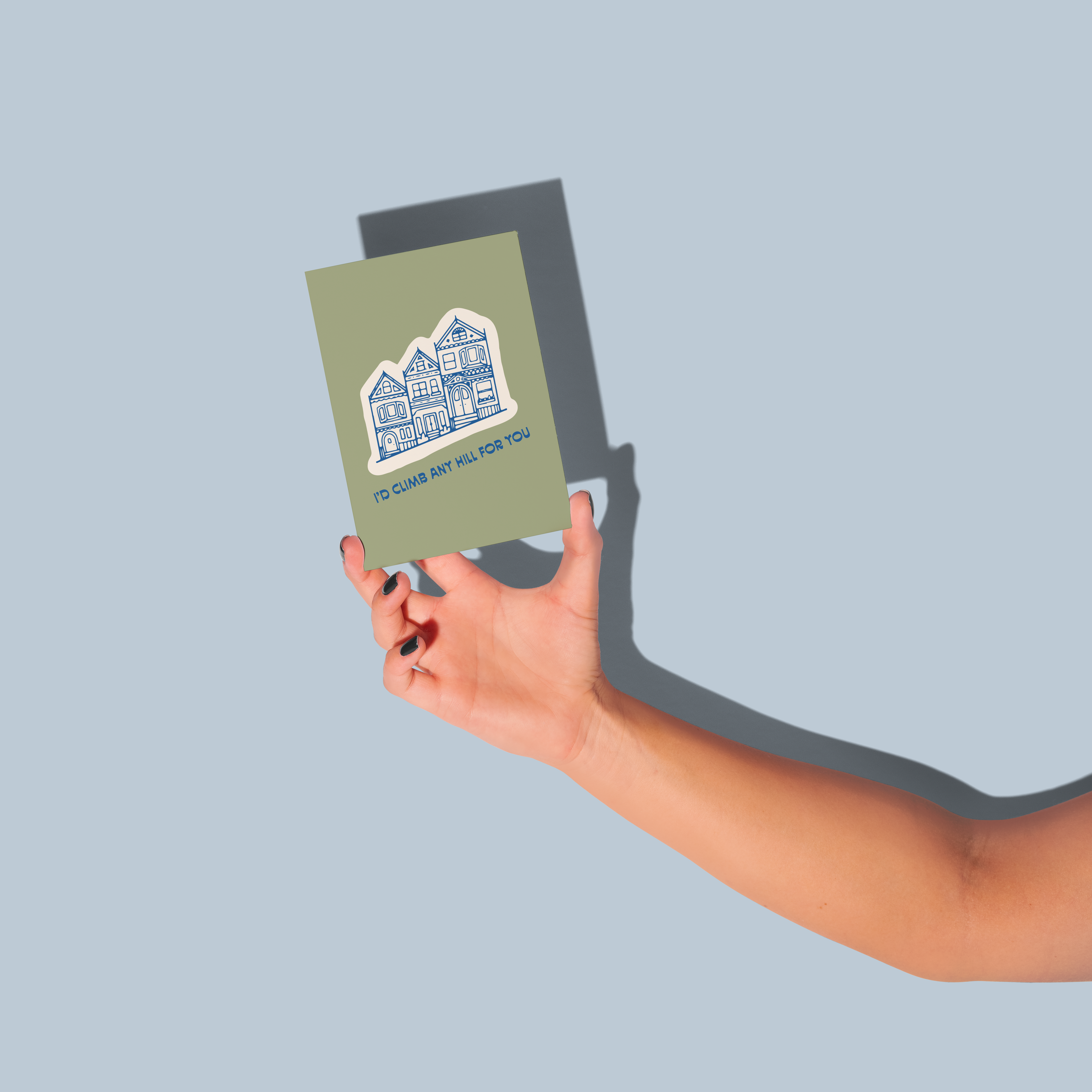 Id Climb Any Hill For You greeting card with houses on a light blue background held in a hand.