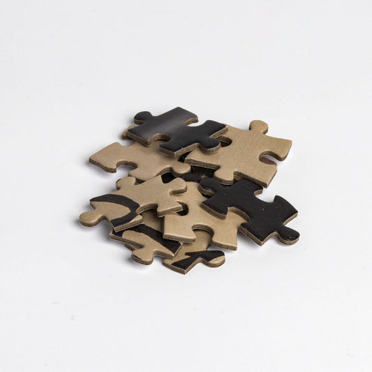 Five brown and black puzzle pieces on a white background, Magritte-inspired. Puzzle, René Magritte, This is not a pipe.