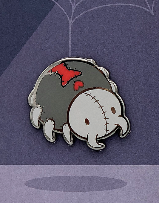 Itsy Bitsy Enamel Pin featuring a cartoon black widow spider with patches and a heart on a purple web background.