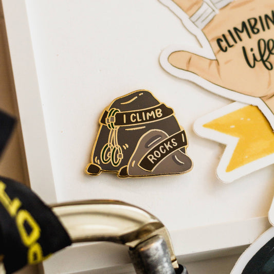 Backpack-shaped enamel pin with I Climb Rocks text and included rock climbing-themed stickers.