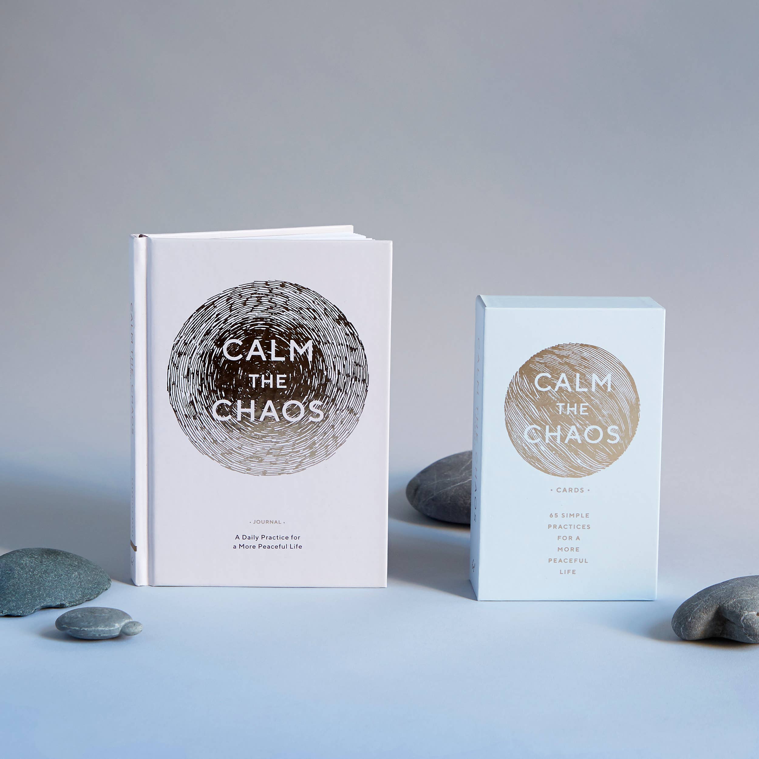Calm the Chaos Cards mindfulness set displayed upright next to gray stones.