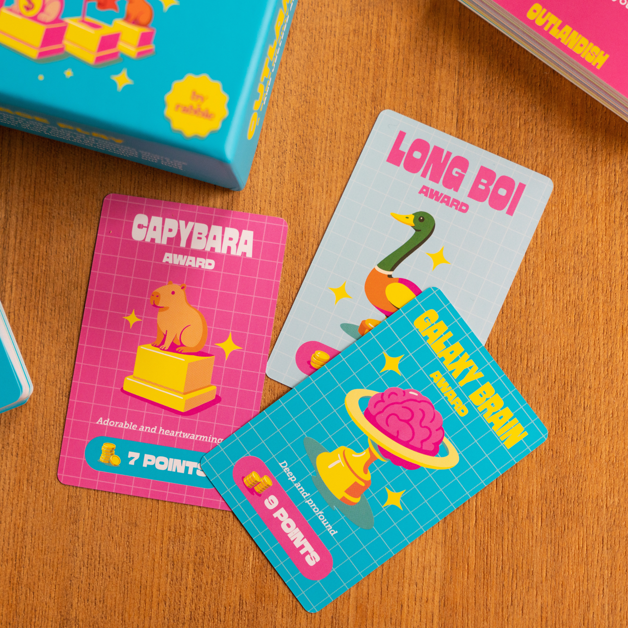 Three Outlandish award cards from the silly questions game, showing a capybara, a goose, and brain artwork.