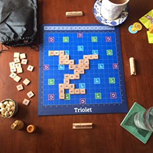 Triolet board game with tiles and score holders on a wooden table. Snacks and drinks are also visible.