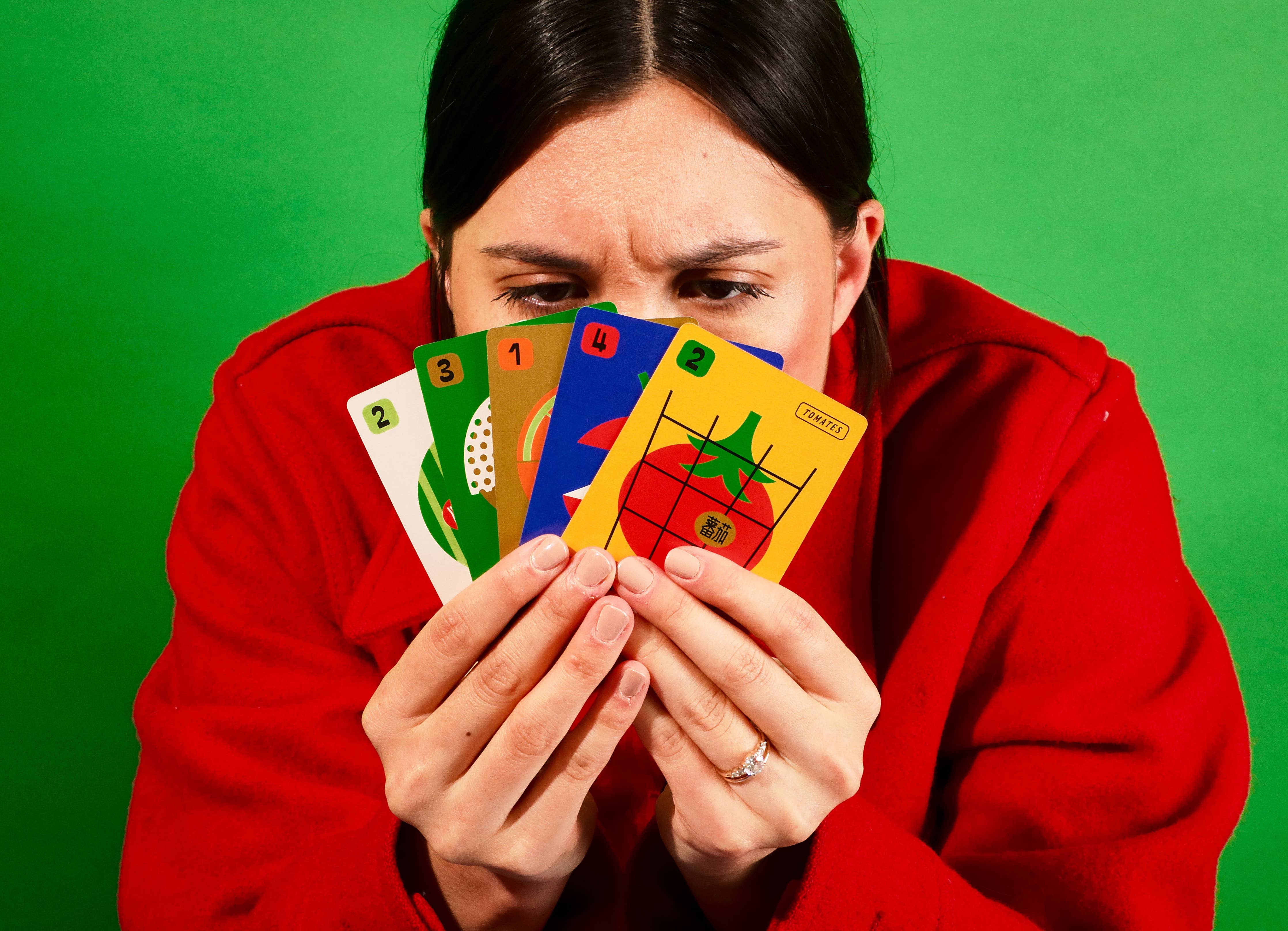 Fruit Boss card game cards displayed on a green surface. Person in red jacket present.