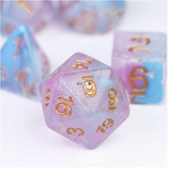 Flare of Ambition RPG Set pink and purple die with gold numbers surrounded by other colorful dice.