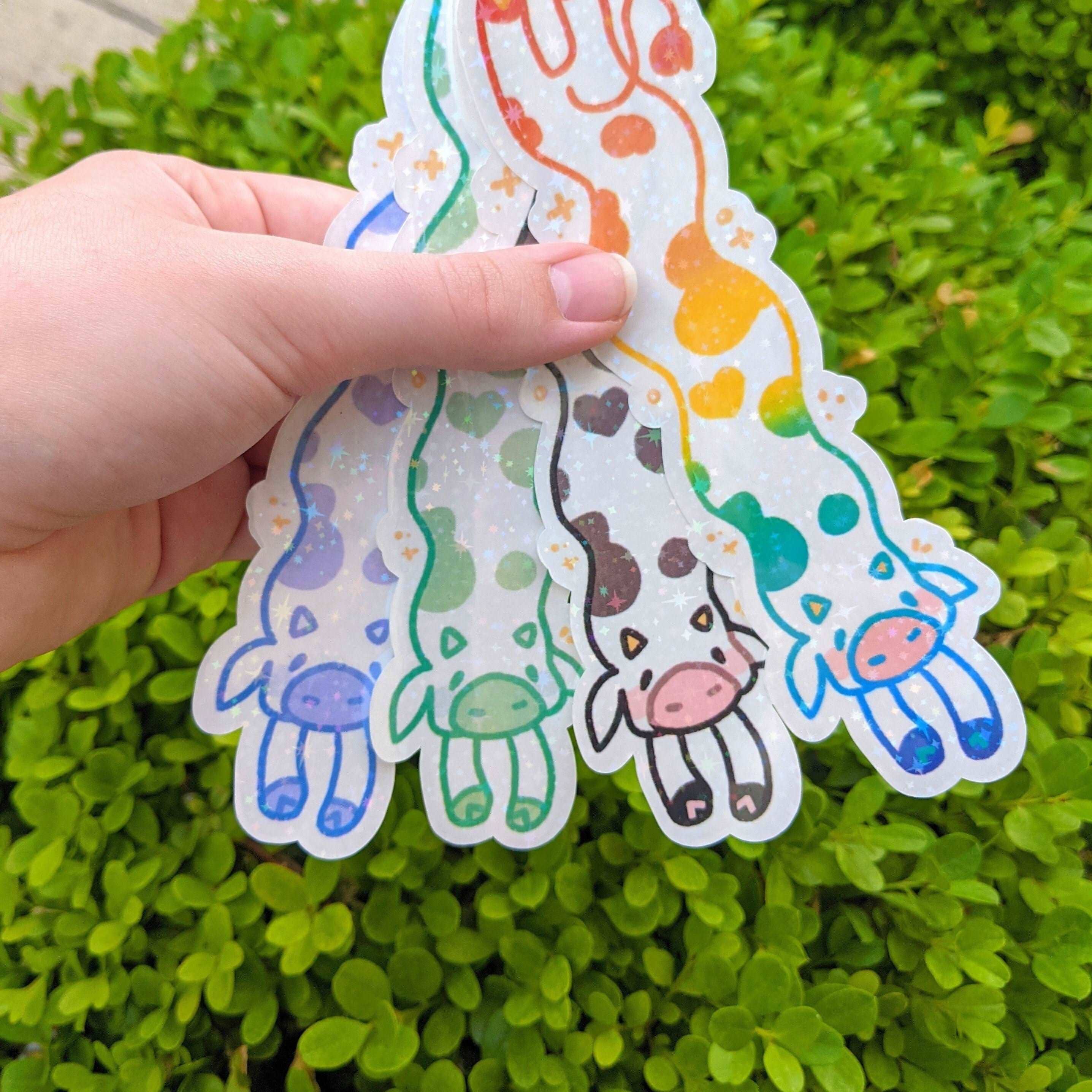 Three MORE Sparkly Long Cow Stickers featuring cartoon giraffes and colorful spots held in a hand.