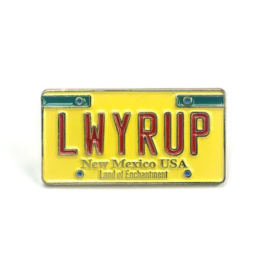 Gold enamel pin shaped like a New Mexico license plate with red letters LWYRUP and text Land of Enchantment.