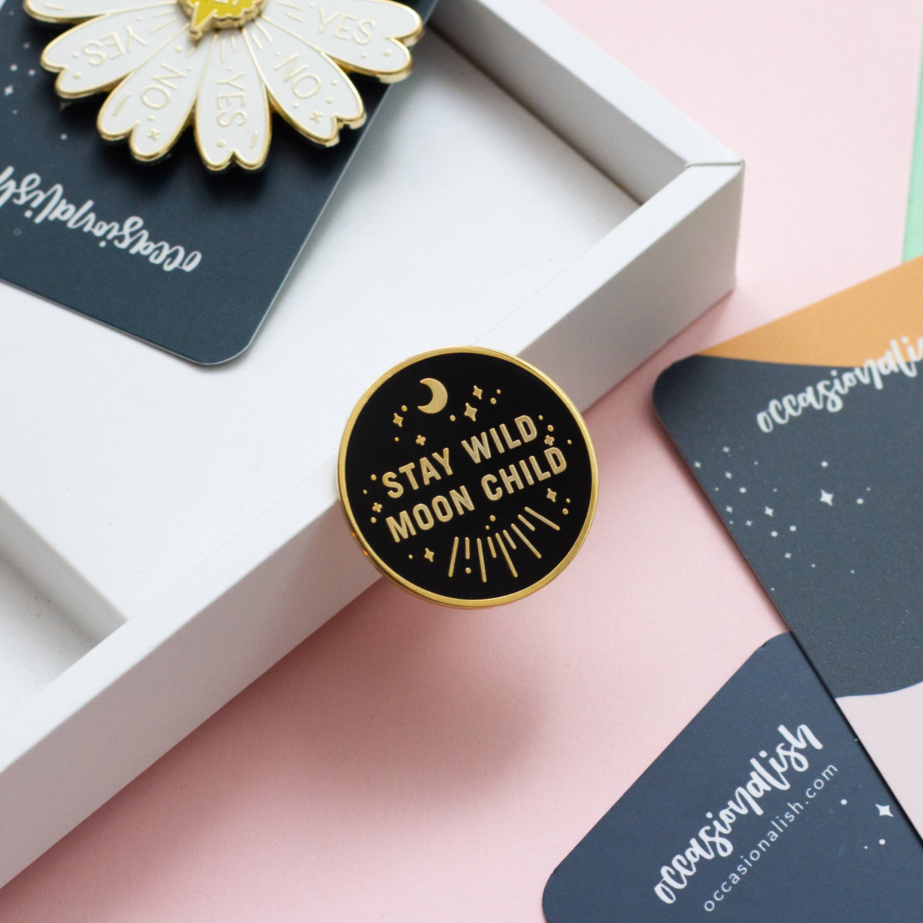 Stay Wild Moon Child enamel pin in black and gold with stars and moons design.