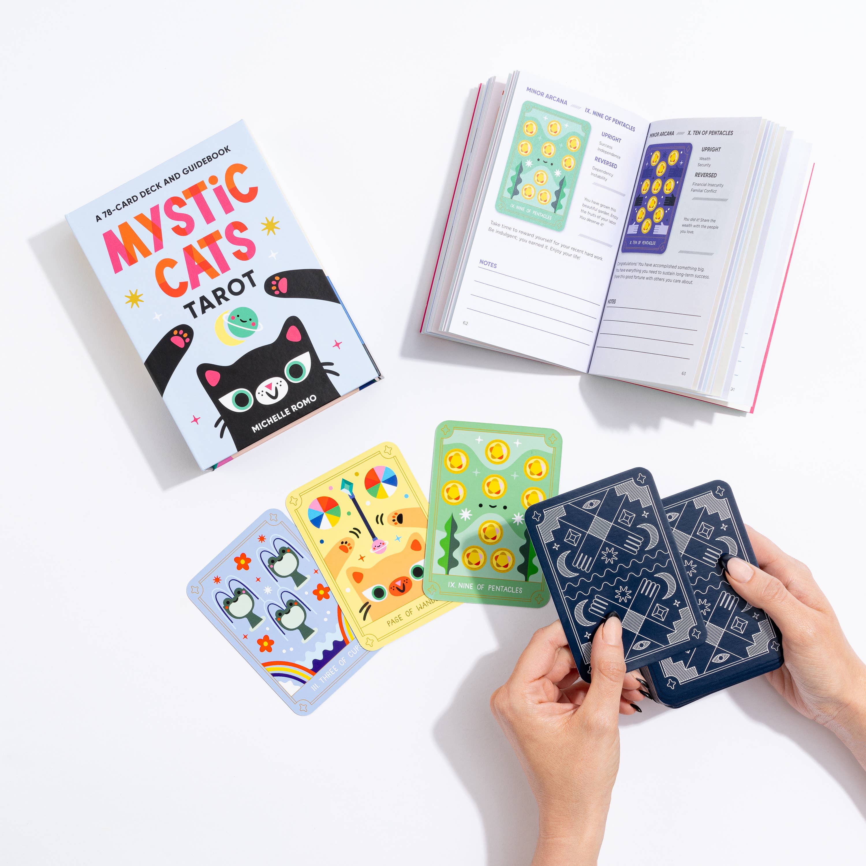 Mystic Cats Tarot 78-card deck with kawaii cat illustrations and guidebook held in two hands above a table.