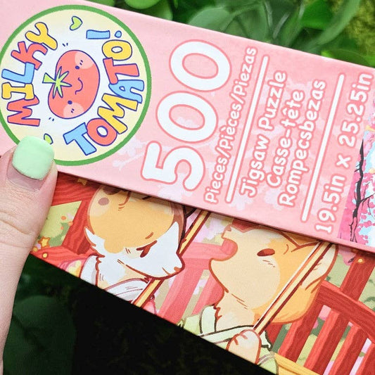 Kimono Kitties 500-Piece Puzzle box held by a hand with green nails.