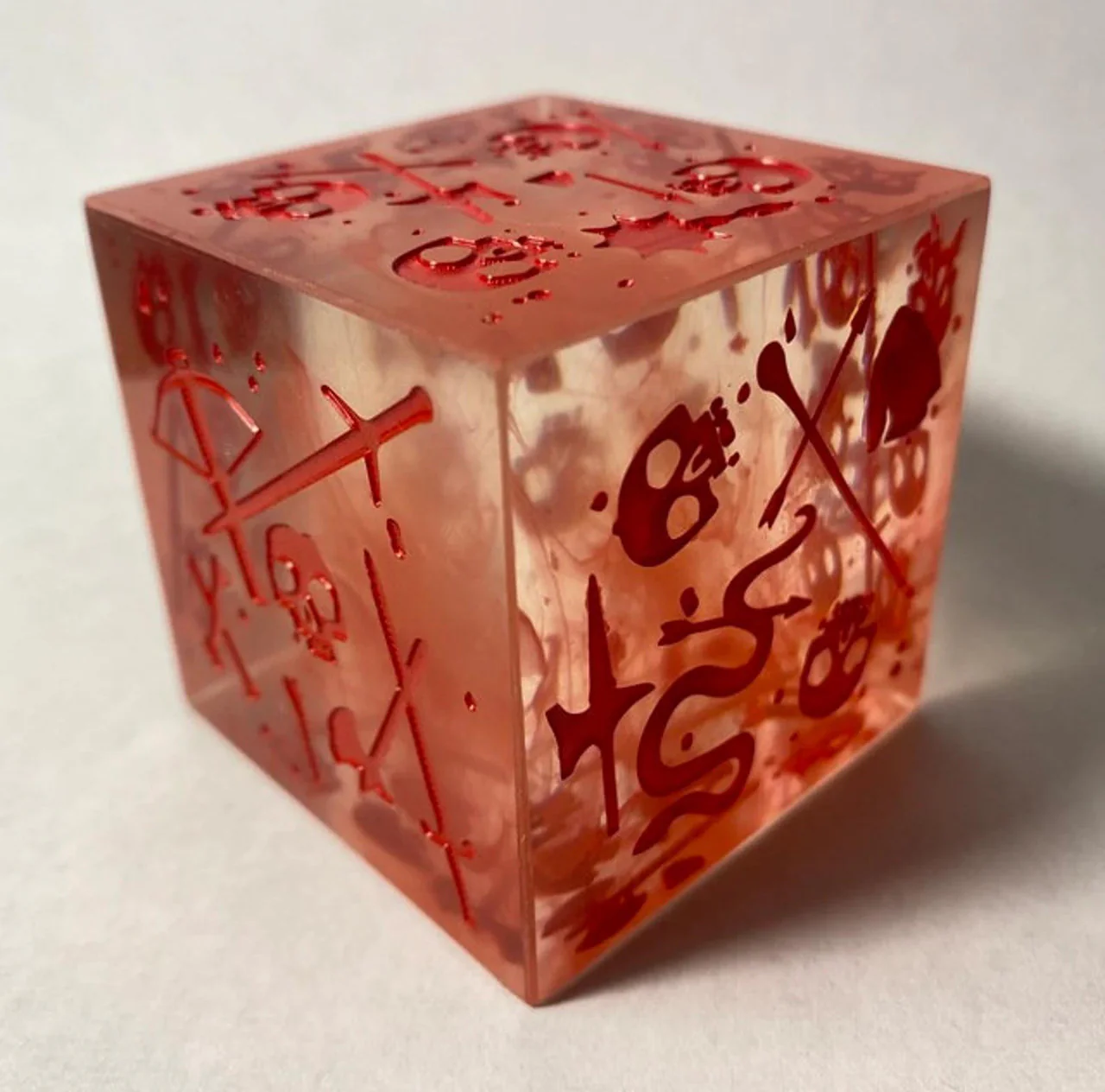 1 Bloody Gelatinous Cube Mini and dice with red abstract symbols inside.