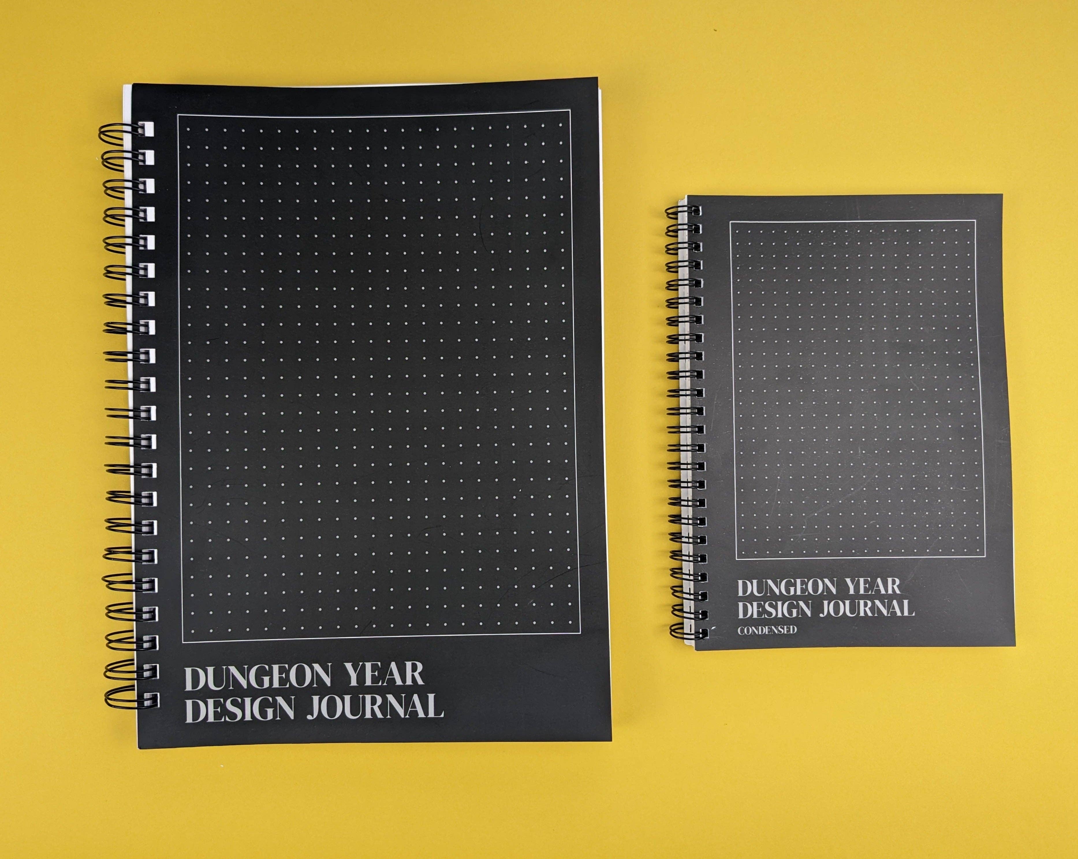 Two black Dungeon Year Design Journal notebooks in large and small sizes.
