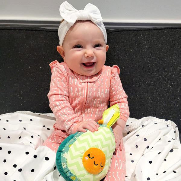 Picnic Baby outfit with white headband shown on baby holding sensory toy, seated on white polka dot blanket.