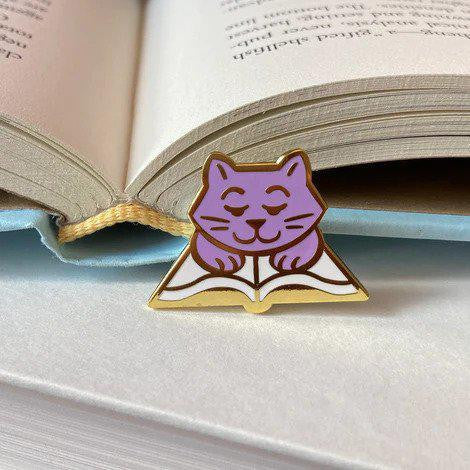 Purple cat on an open book enamel pin.