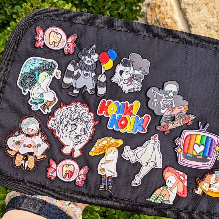 Black bag featuring colorful cartoon pins: animals, mushrooms, and the Cute Kitty Phone Enamel Pin.