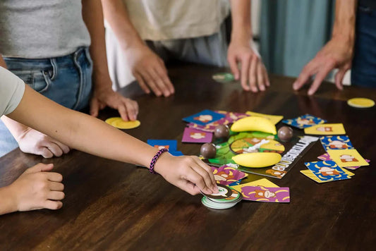 800 Pound Gorilla card game with bananas and tokens on a wooden table, played by four people.