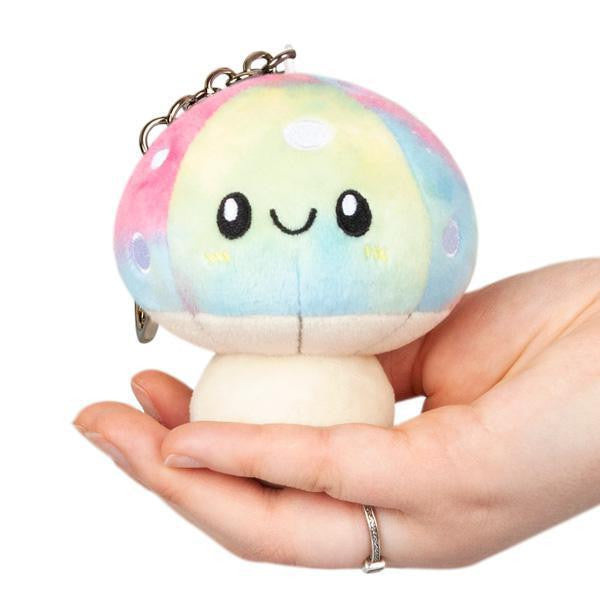 Mushroom Tie Dye 3 Micro Squishable keychain with a smiling face, held in a hand against a white background.