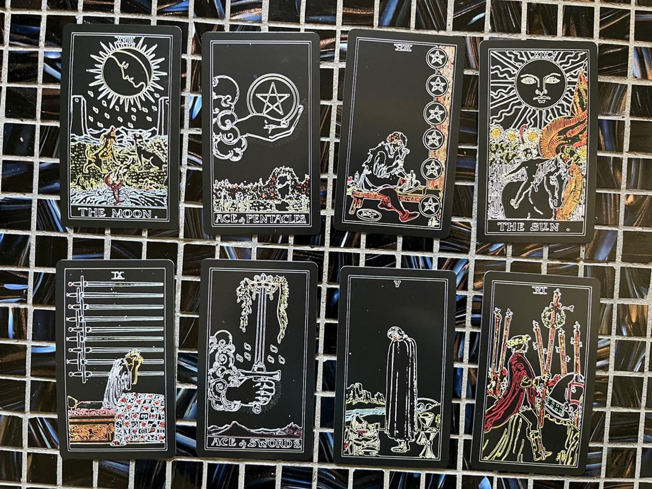 The Luminous Tarot Classic 1909 Smith Rider deck and guidebook with eight black tarot cards featuring white line art.
