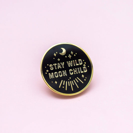Stay Wild Moon Child enamel pin, round black hard enamel with gold trim, stars, crescent moon, and pink background.