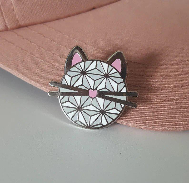 Geometric white cat face hard enamel pin with pink details.