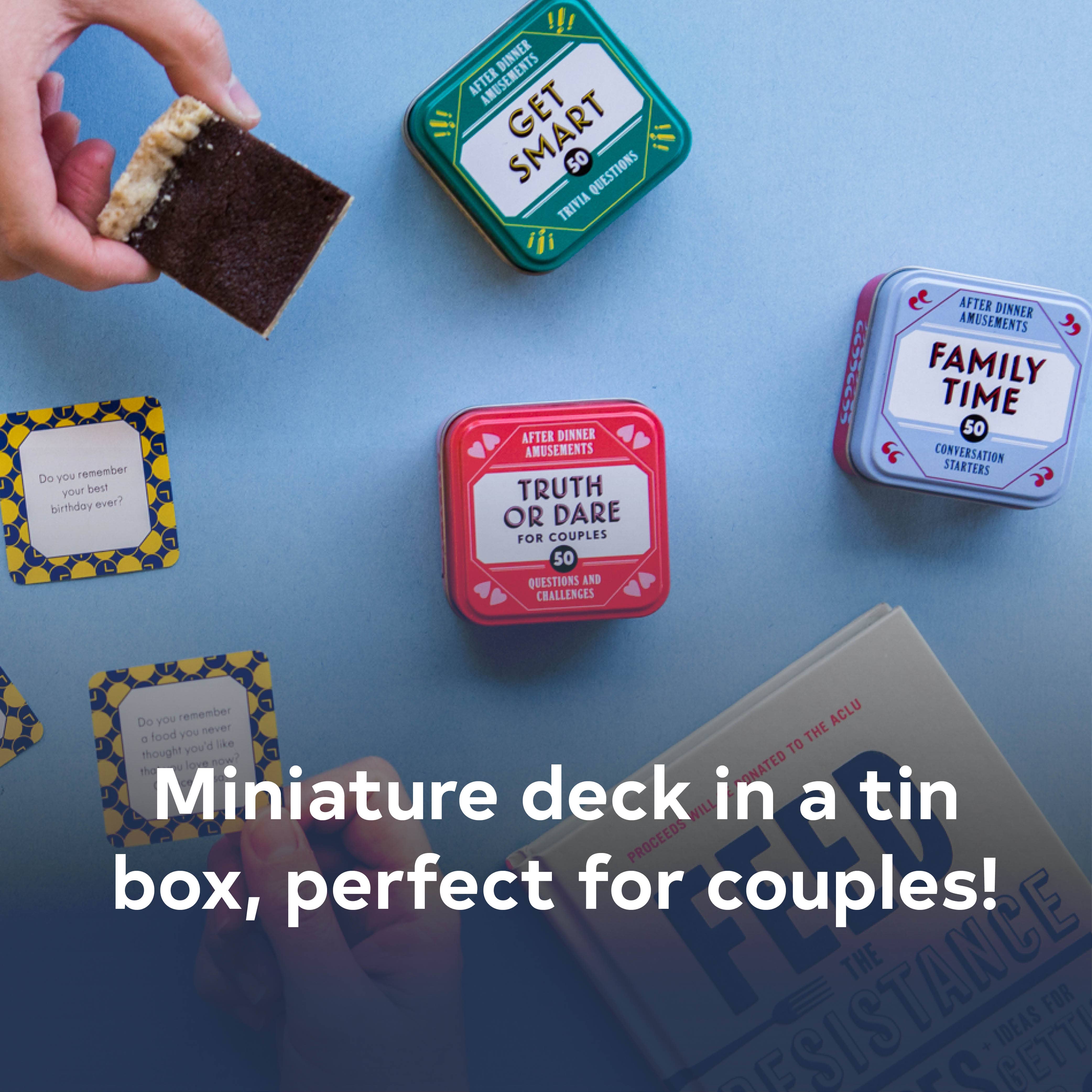 After Dinner Amusements: Truth or Dare for Couples tins and a card held by a hand on a blue table.