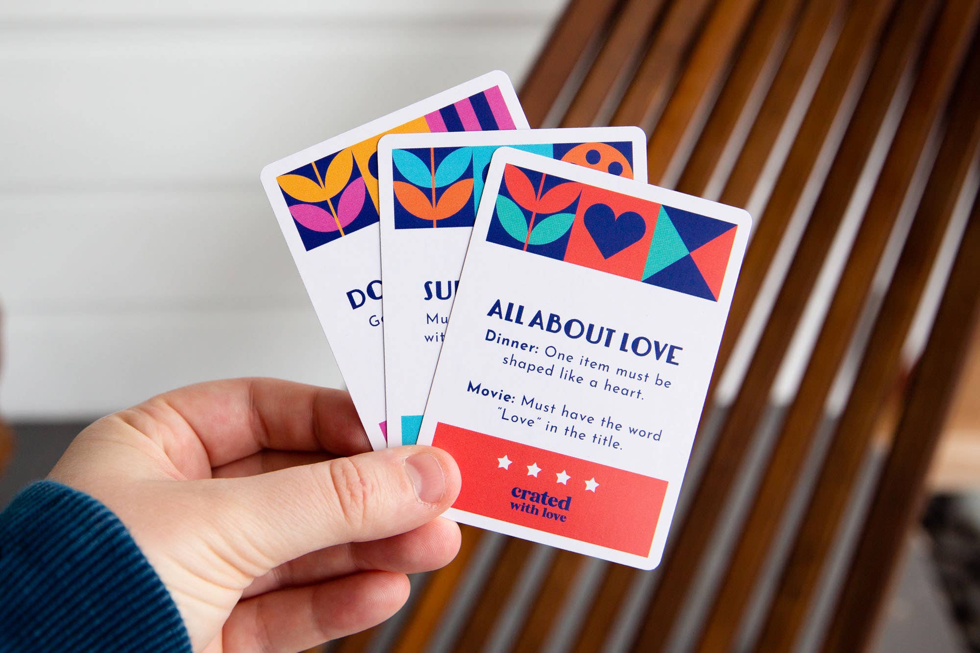 Hand holding three Mix It Up Date Night Generator cards displaying colorful relationship prompt cards.