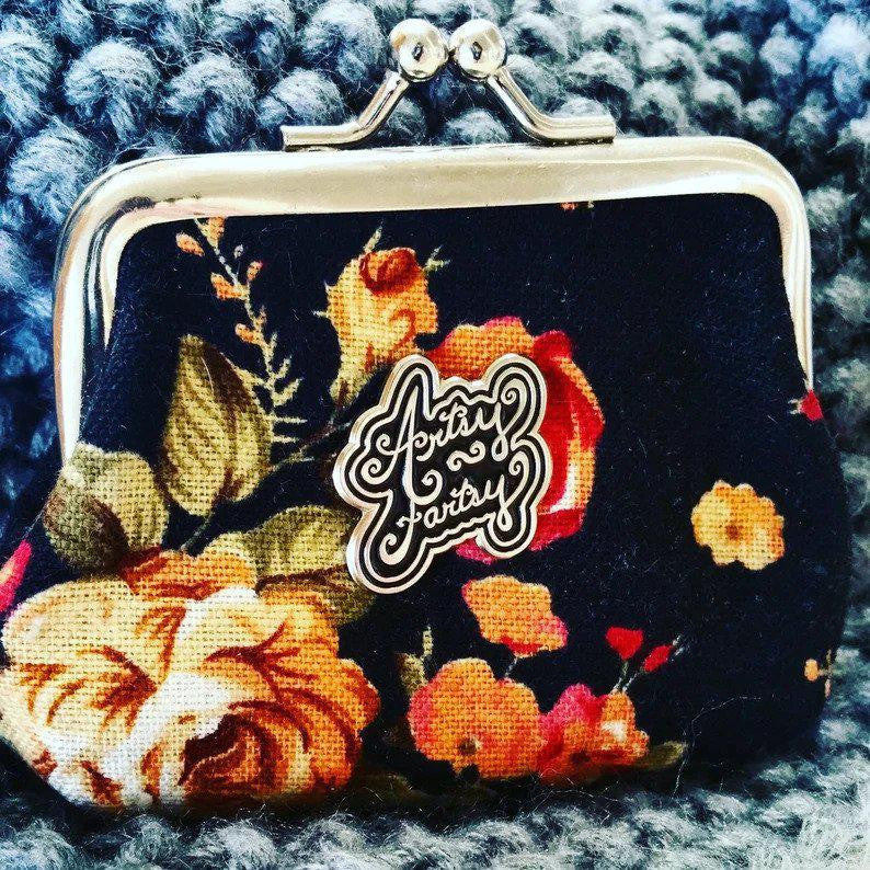 Floral coin purse with metal clasp, enamel pin accent, and textured knit patch.