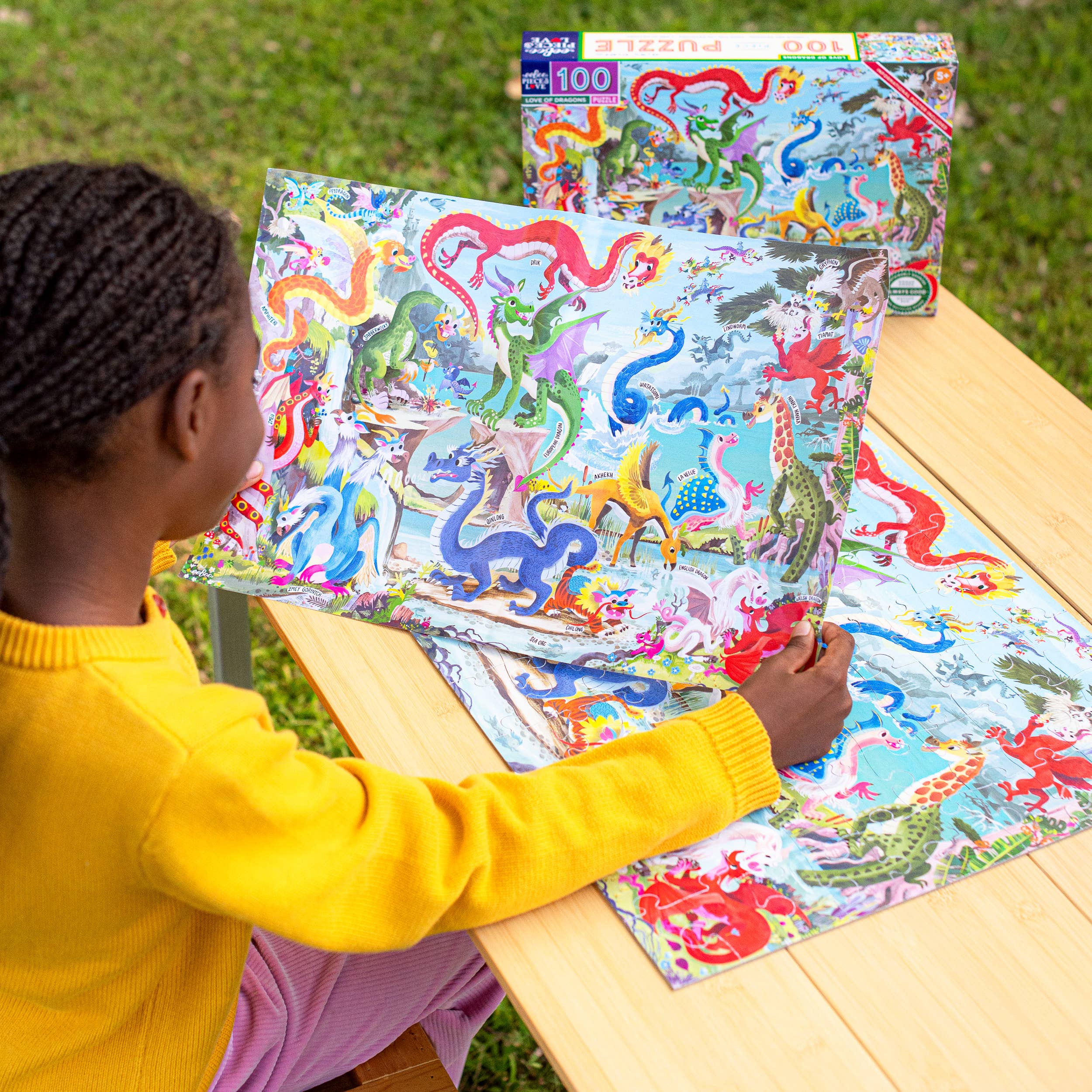 Love of Dragons 100 Piece Puzzle being assembled on a wooden table outdoors.