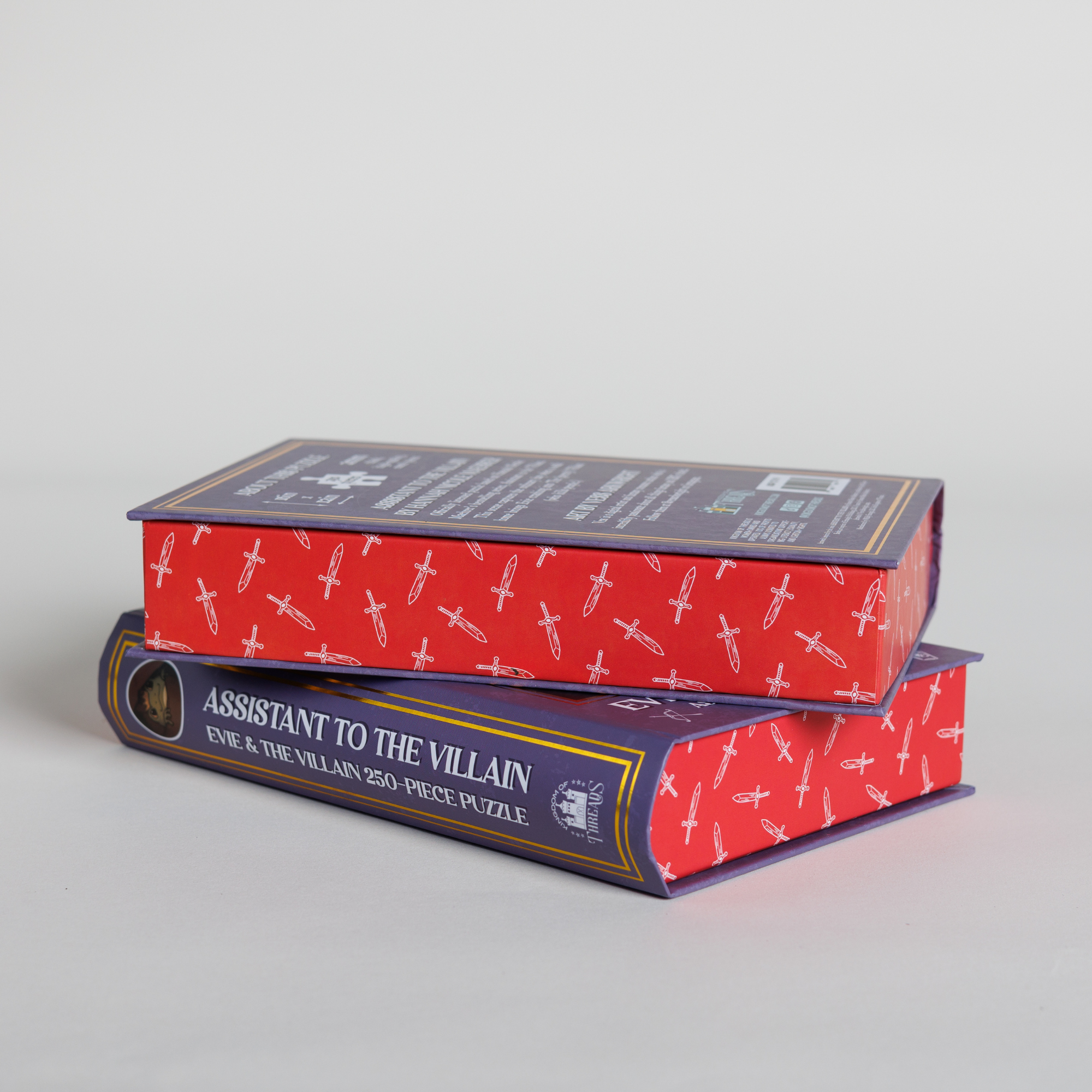 Evie & Villain Keepsake Puzzle set: two fantasy puzzles in book-shaped boxes labeled “Assistant to the Villain” on spine.