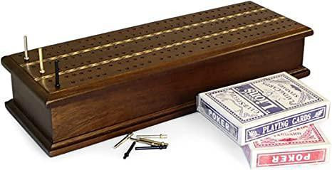 Wooden inlaid cribbage board with pegs and two decks of cards on a white surface.