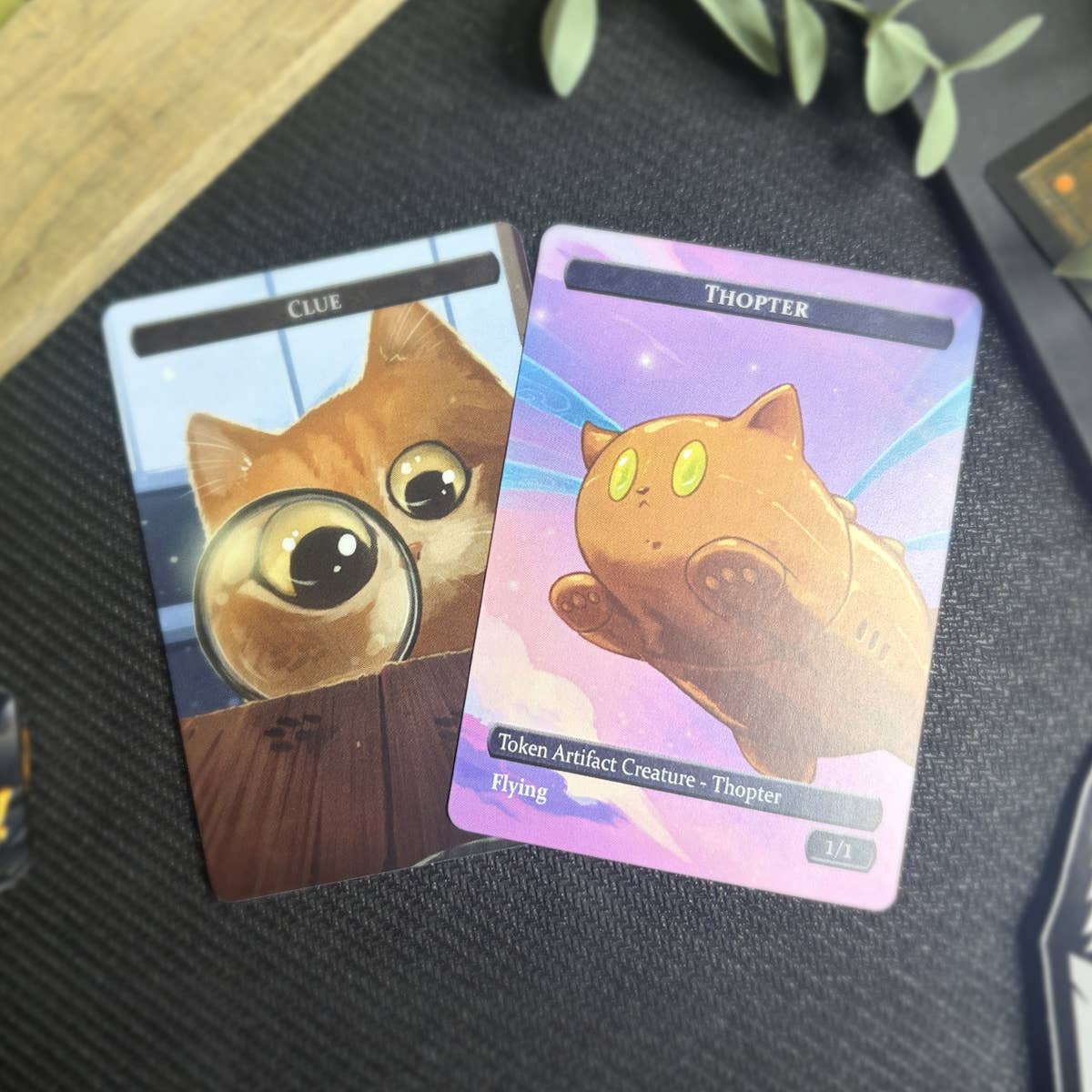 Thopter & Clue Token Set: one card features a cat with magnifiers, the other a flying brown cat-like Thopter.
