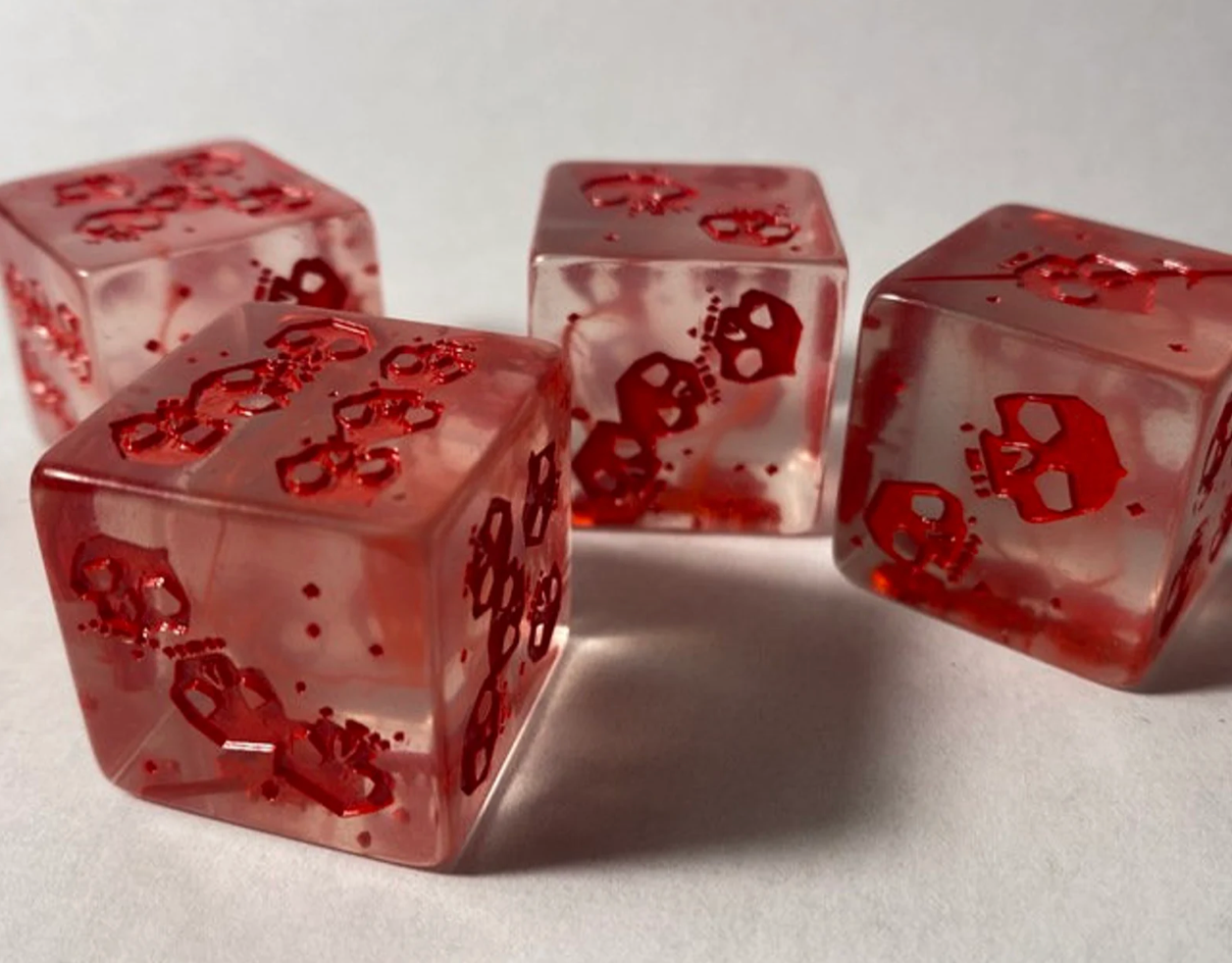 1 Bloody Gelatinous Cube Mini and Dice with red skulls and glitter on a white surface.