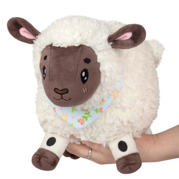 Mini Squishable Spring Lamb plush with white body and blue floral bandana, held in a hand.